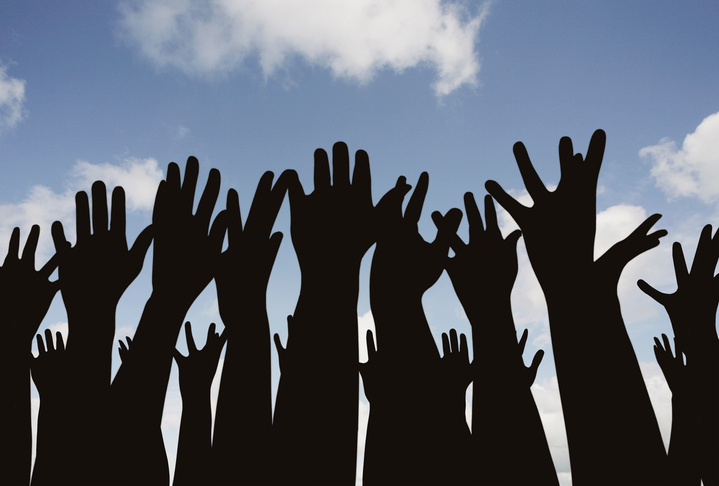 Hands raise into the air with a blue sky background behind.